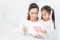 Little aisan girl daughter congratulates mom and gives a heart postcard. Royalty Free Stock Photo